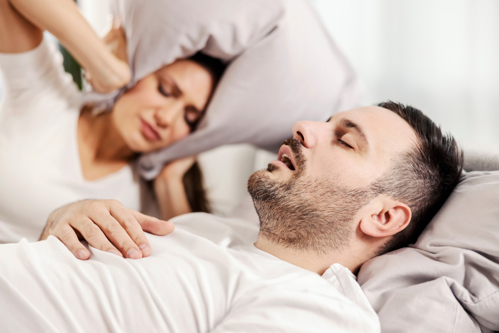 stock photo a man snoring and sleeping in the bed while woman is annoyed of it