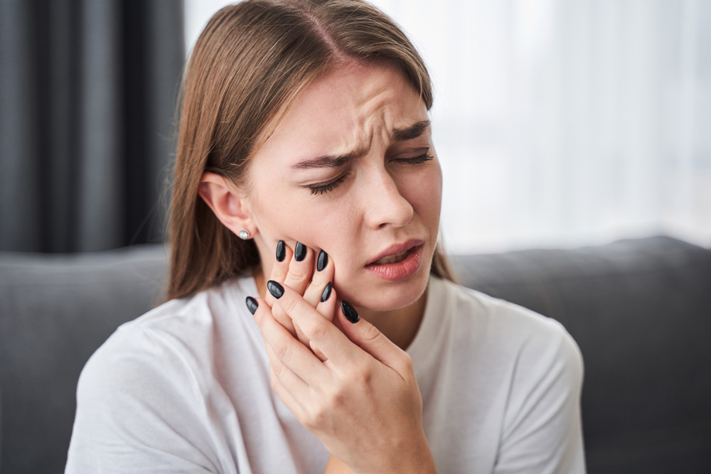 stock photo awful toothache frustrated young women suffering from toothache while sitting on the sofa at home